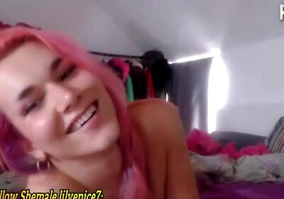 A pink-haired, small-breasted transgender girl from the UK teases in front of the camera